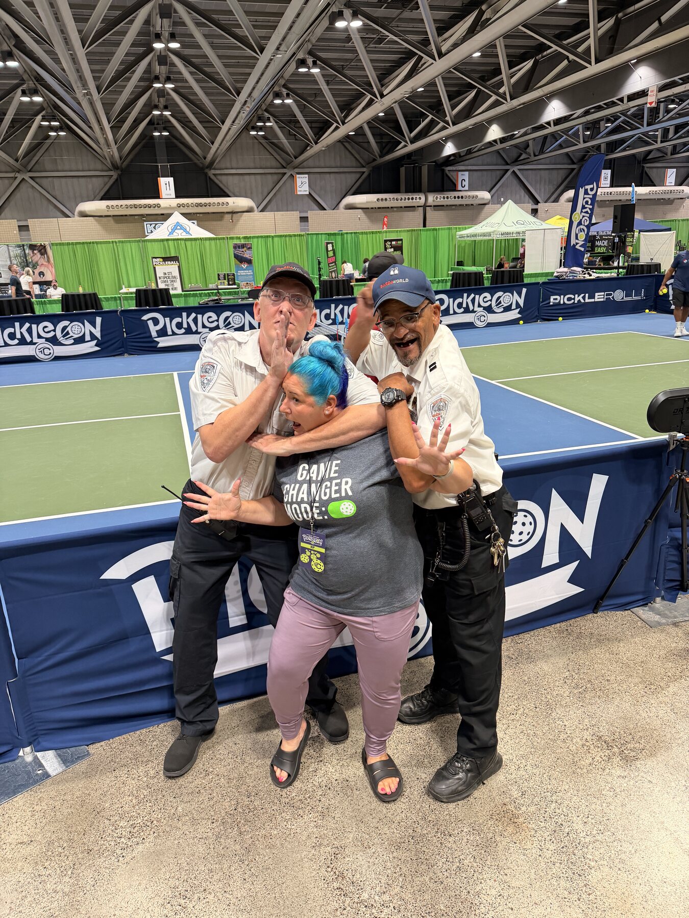 People posing playfully beside a PickleCon court