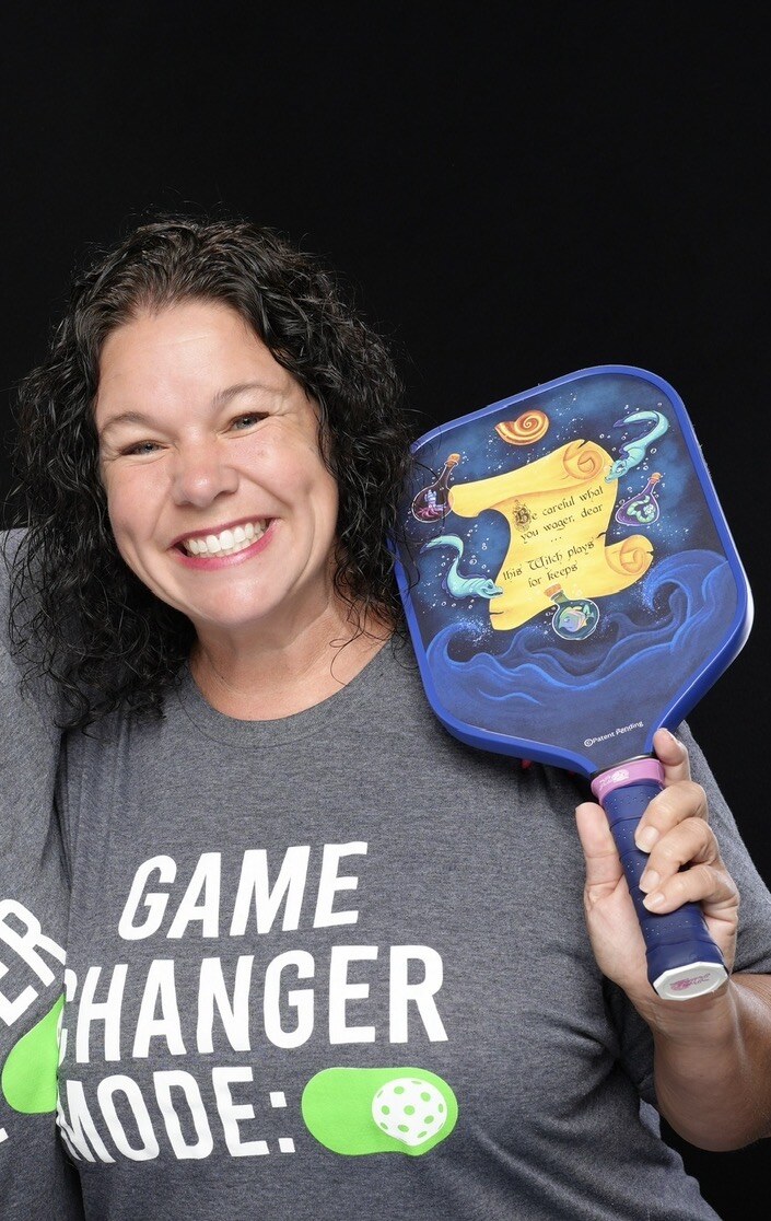 Carrie Harris smiling with a decorated pickleball paddle