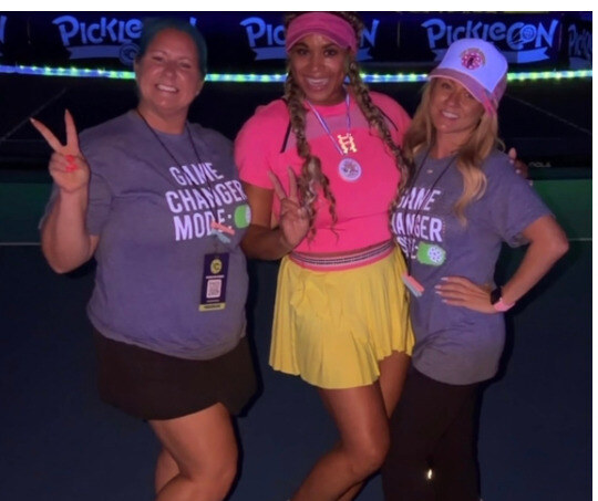 Three attendees in costume laughing together during a social challenge